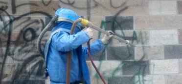 Graffiti being removed from a brick building